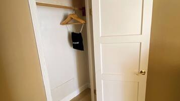 A hallway with a white door, a wooden hanger, and a black bag on a wall.