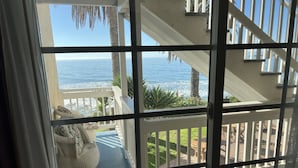 A view from a balcony with a railing, overlooking a wooden deck and a body of water. - Cliff House Inn On The Ocean (Ventura)