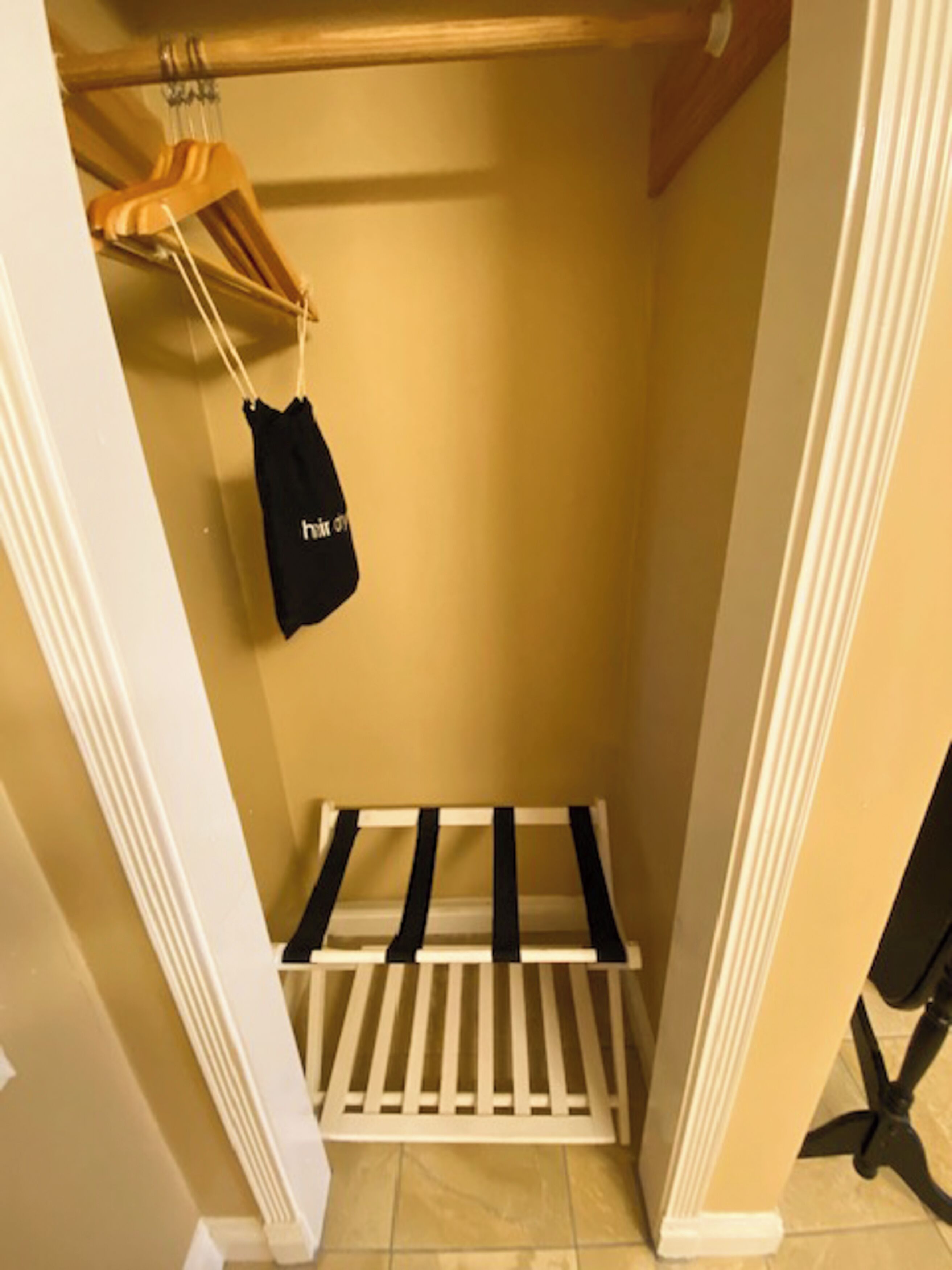 A narrow hallway with a white door frame, a beige wall, and a black and white rack.
