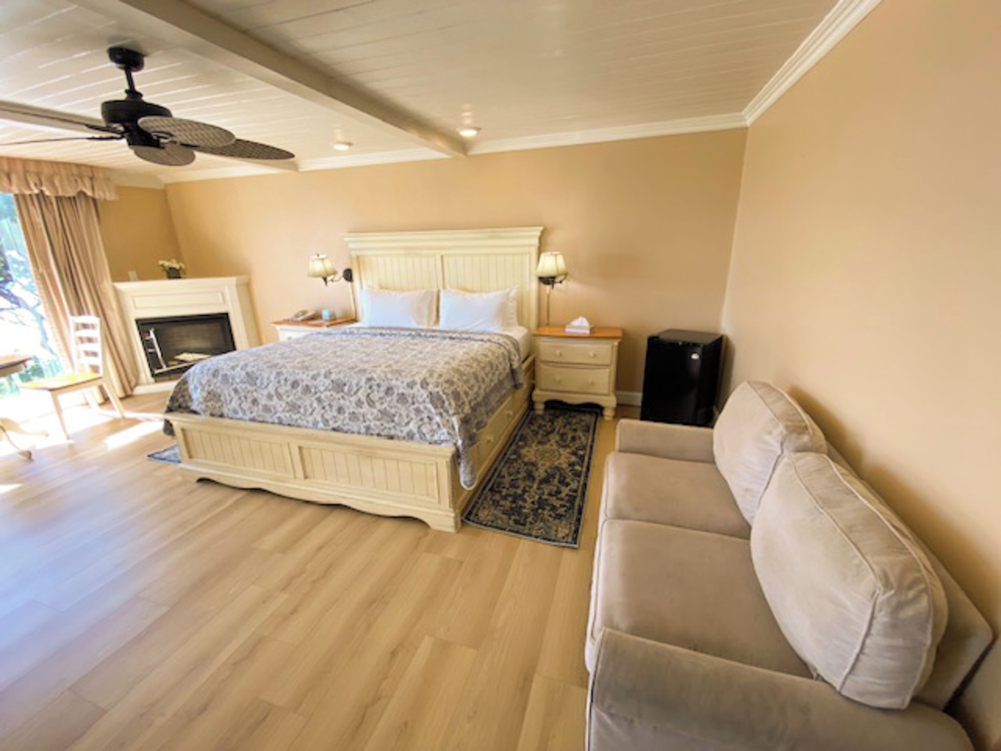 Une chambre à coucher comprenant un lit, des tables de chevet, une lampe, un radiateur, un canapé et un ventilateur de plafond.