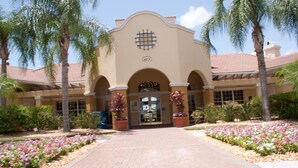 A building with a beige facade, arched entrance, and a tiled roof.