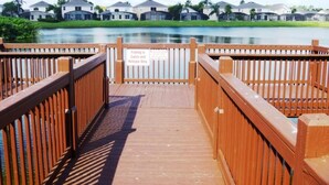A wooden boardwalk leading to a lake with a sign indicating fishing is catch and release only.