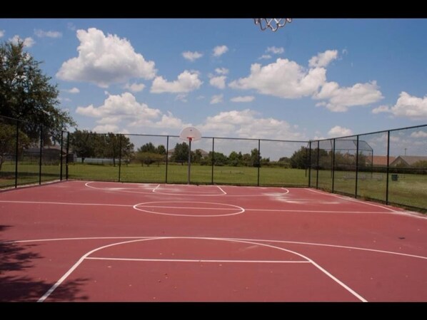 An outdoor basketball court with a clear sky and clouds. - Alamo Vacation Townhomes (Orlando)