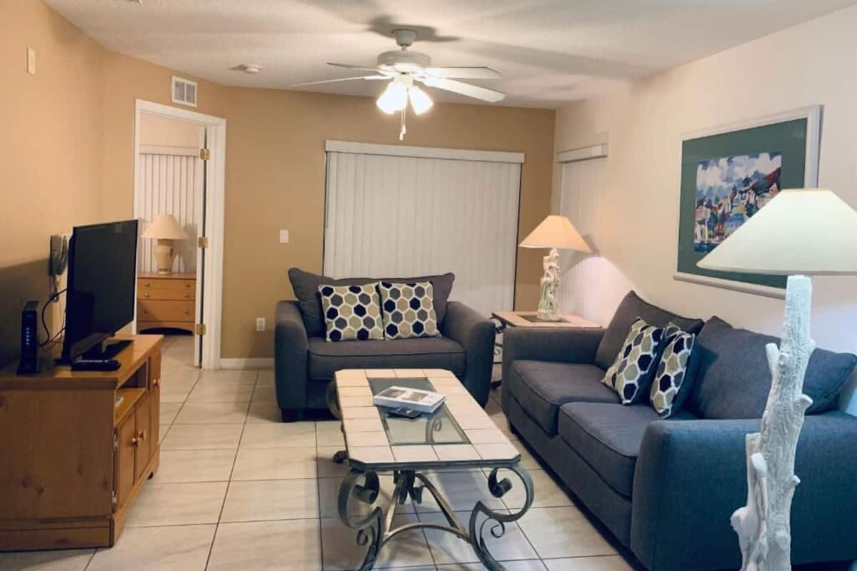A living room with two sofas, a coffee table, a TV, and a ceiling fan.