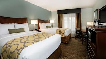 A hotel room with two beds, a desk, a television, and a coffee maker.