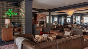 A spacious living area with leather sofas, a fireplace, and a neon sign reading "Alpine." - The Wentworth (Jackson)
