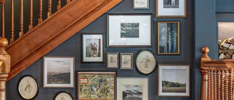 A staircase with a wooden handrail and a wall adorned with framed photographs and artwork.