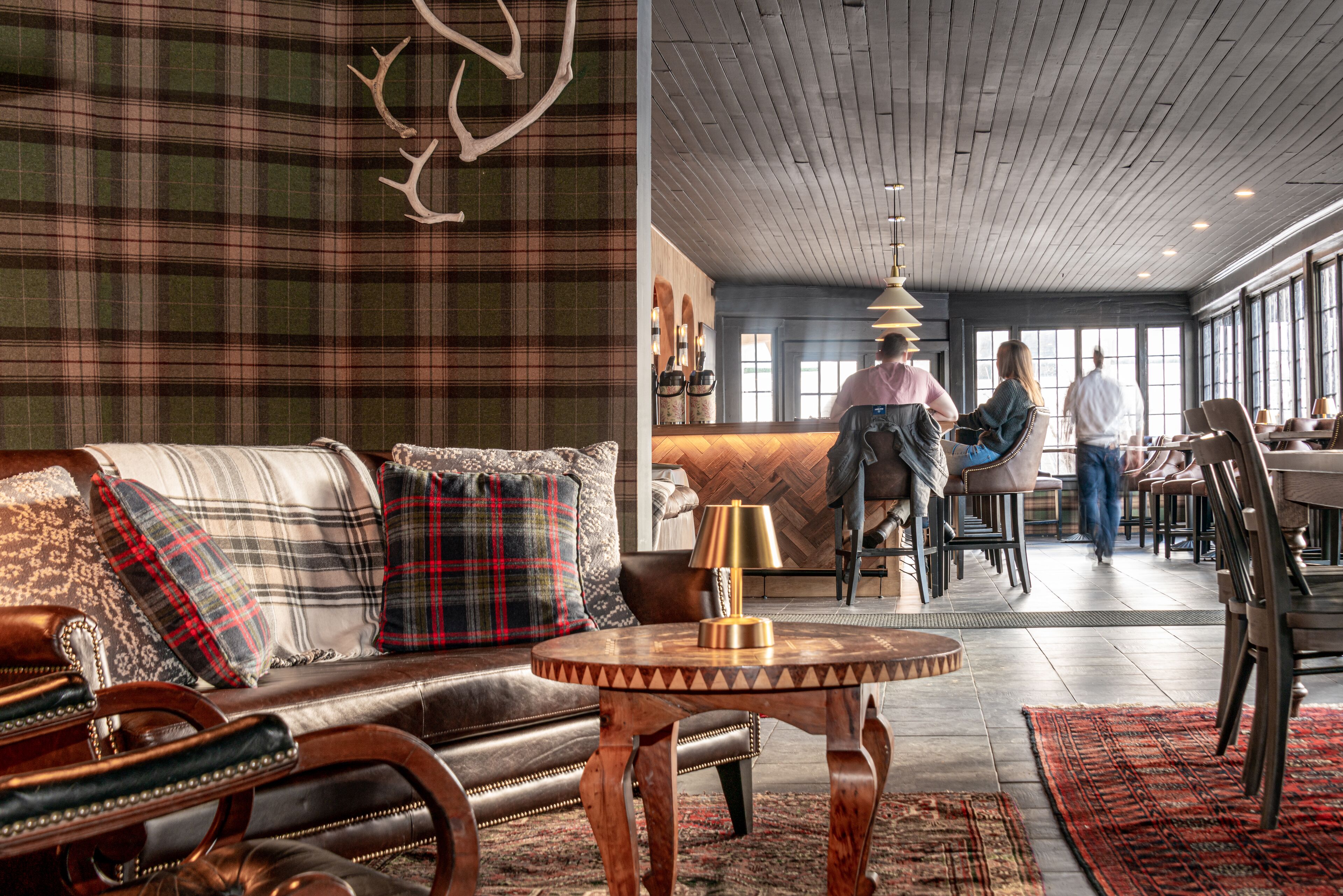 A modern interior with a leather sofa, plaid wall, and a wooden ceiling.
