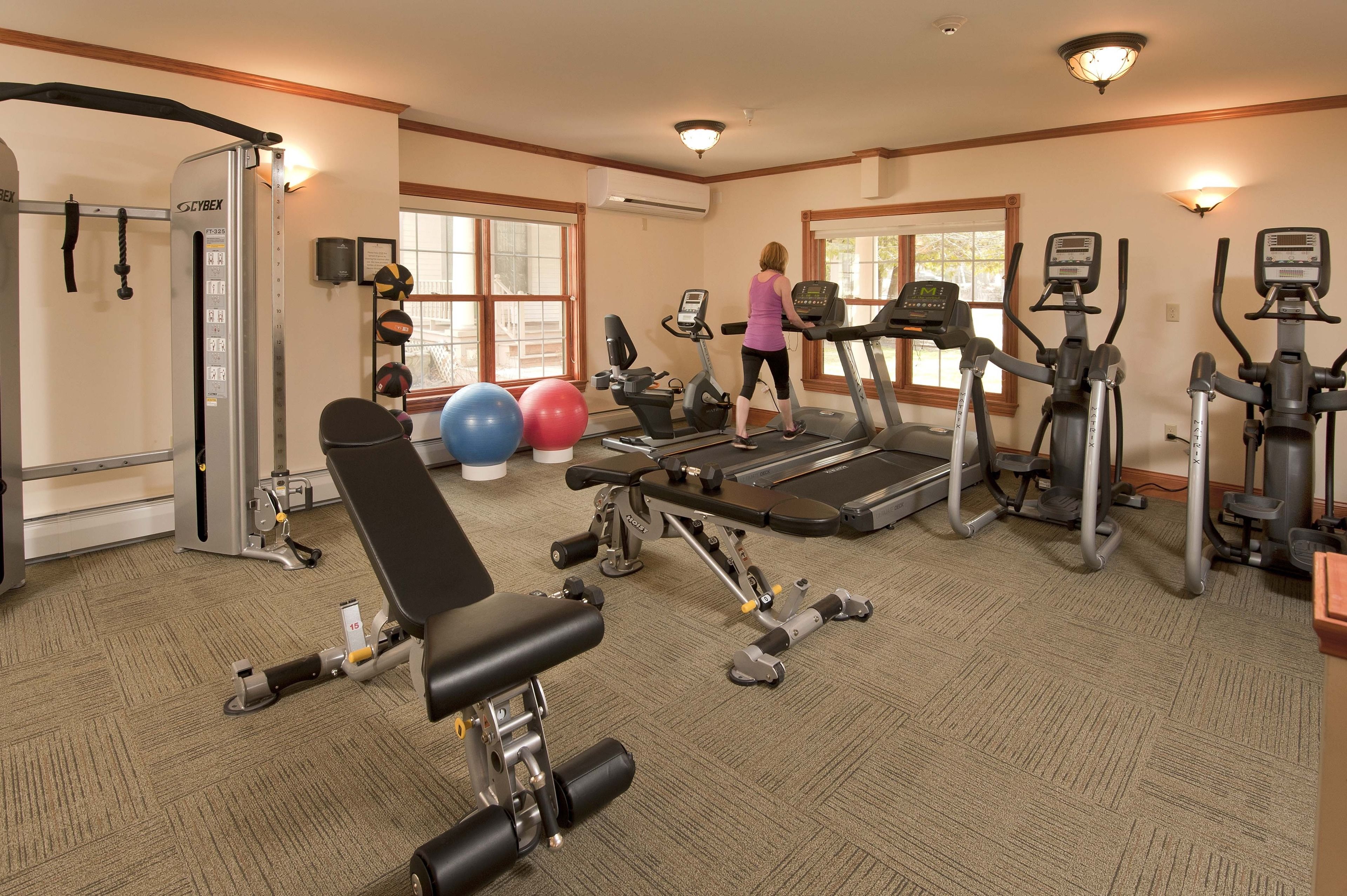 Ein Fitnessstudio mit Laufbändern, Krafttrainingsgeräten und Übungsbällen.