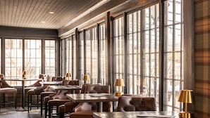 A restaurant with multiple tables and booths, large windows, and a wooden ceiling. - The Wentworth (Jackson)