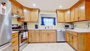 Una cocina con armarios de madera, un refrigerador de acero inoxidable, un horno, un microondas y un lavavajillas.