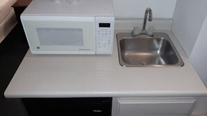 A compact kitchen with a microwave, a stainless steel sink, and a dishwasher. - Iron Horse Inn (Simsbury)