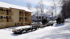 A multi-story building with balconies, a snow-covered ground, and a clear sky. - Iron Horse Inn (Simsbury)