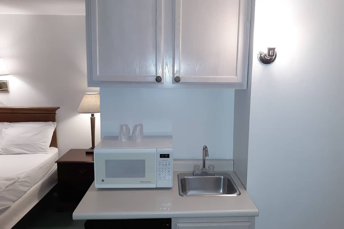 A small kitchenette with a microwave, sink, and cabinets.