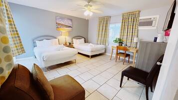 Une chambre d’hôtel avec deux lits, un bureau, une chaise, un ventilateur de plafond et une fenêtre avec des rideaux.