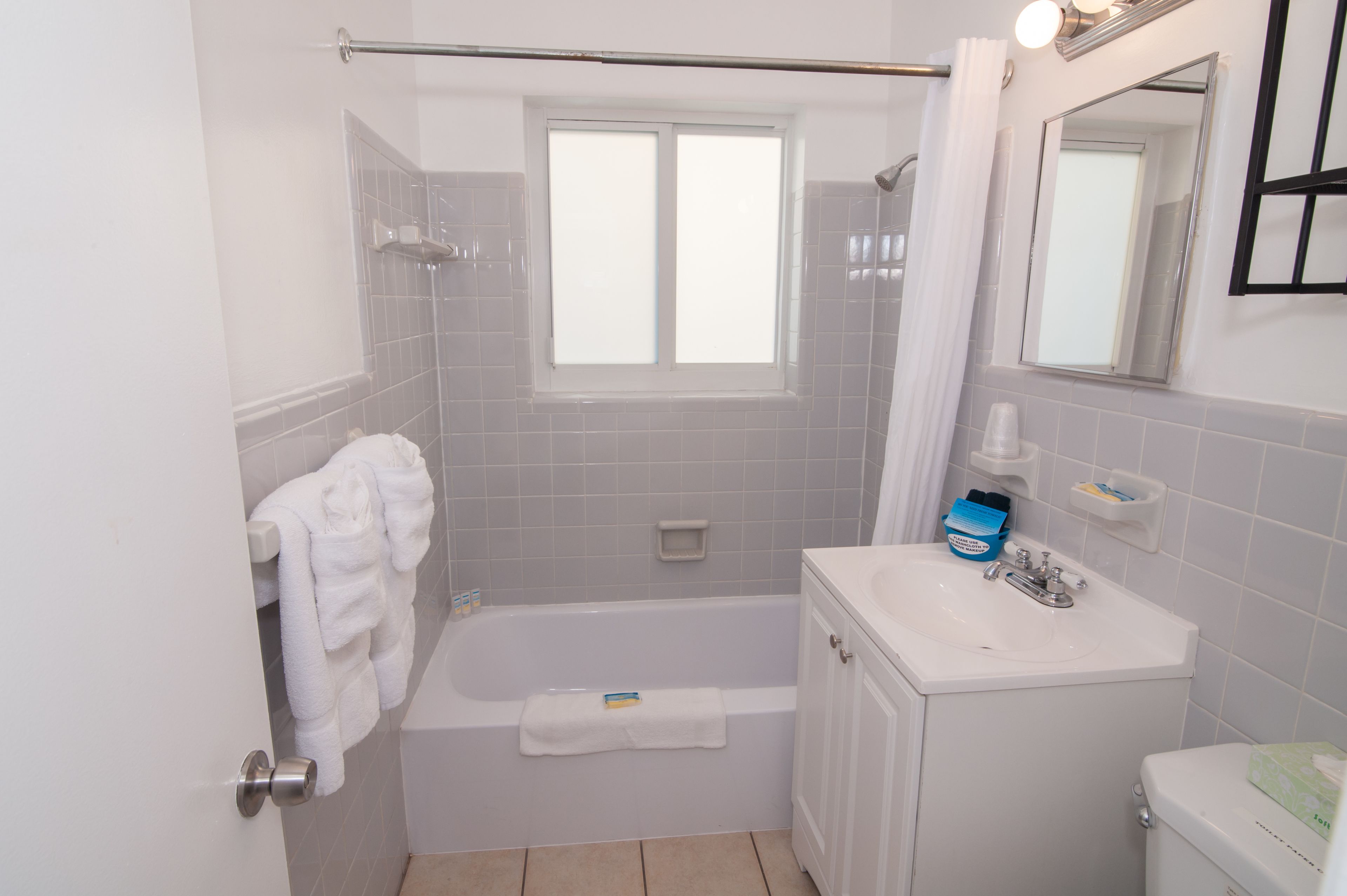 A bathroom with a bathtub, a sink, a toilet, and a window.