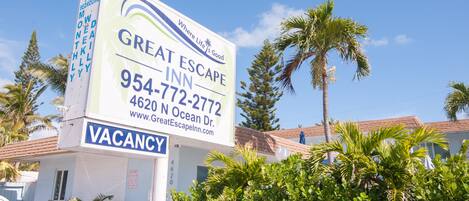 A sign for a hotel named "Great Escape Inn" with a contact number and website.