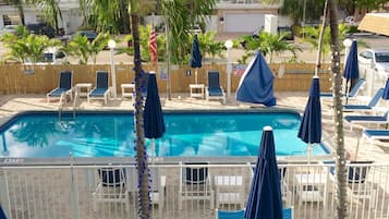 Una piscina al aire libre, sombrillas, sillones reclinables de piscina