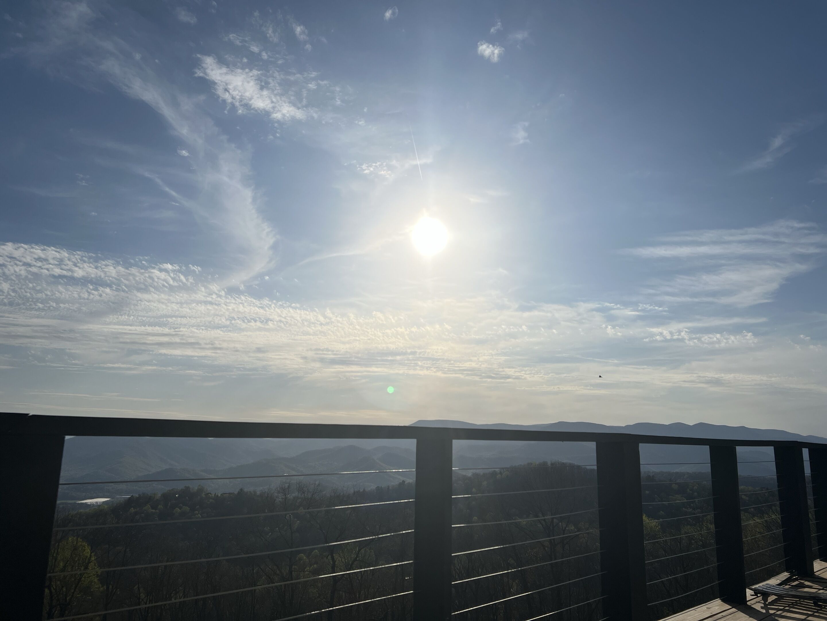 A balcony with a view of a mountainous landscape and a clear sky.