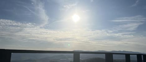A balcony with a view of a mountainous landscape and a clear sky.