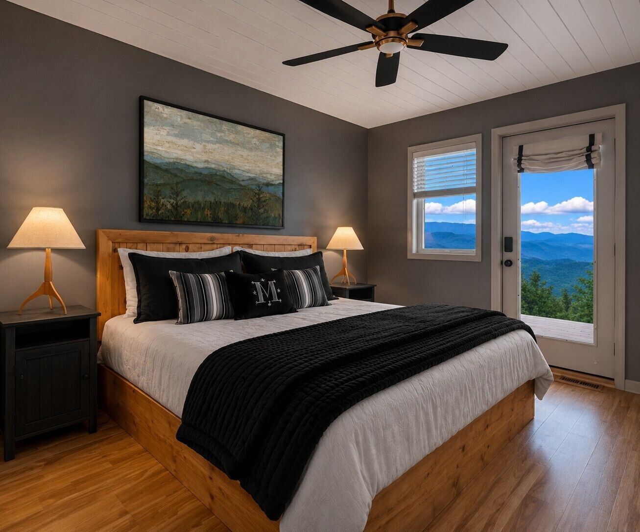 A bedroom with a bed, two bedside tables, a ceiling fan, a window with a view, and a painting on the wall.
