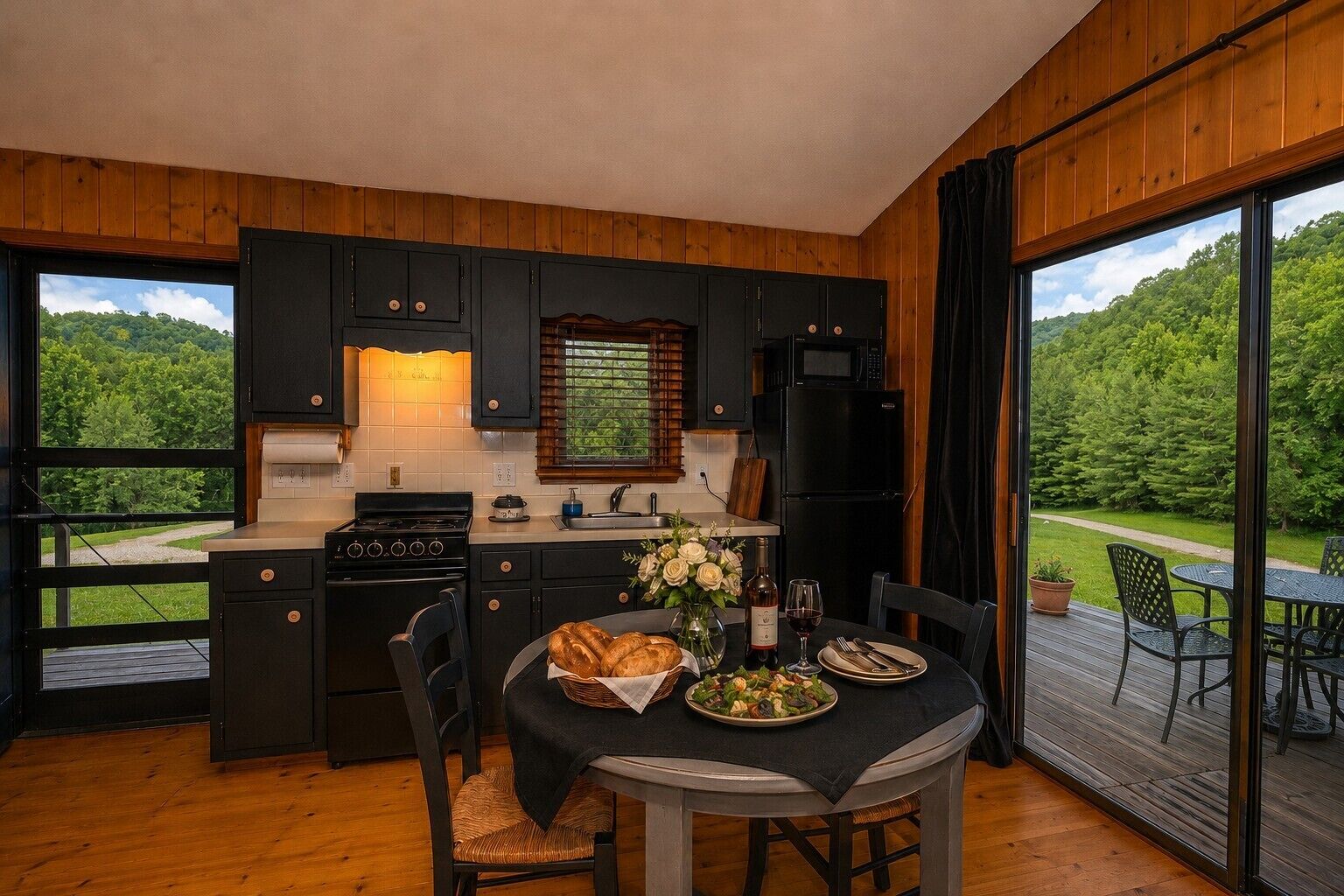 A modern kitchen with dark cabinetry, a central island, and a dining area with a table set for two.