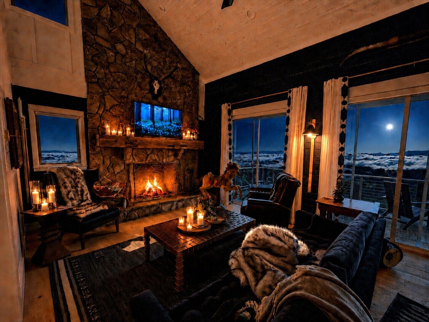 Ein gemütliches Wohnzimmer mit Kamin, Fernseher und Blick auf die Berge.
