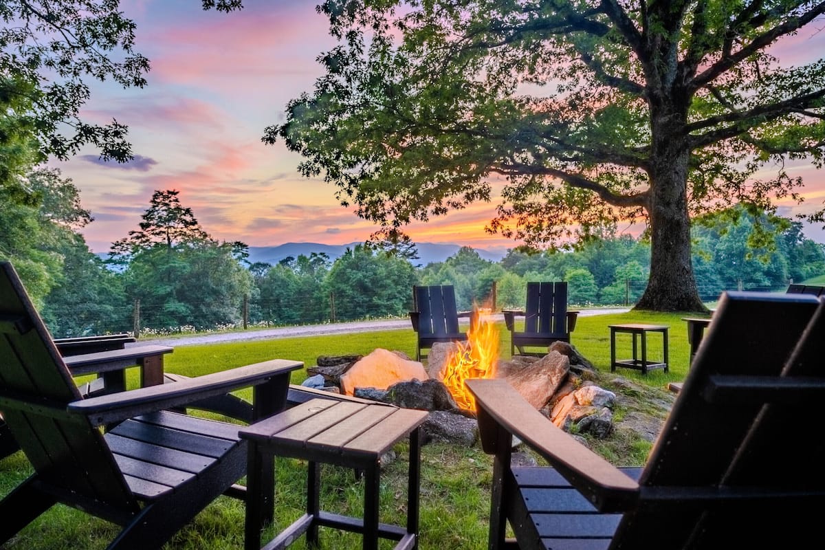 A campfire with chairs and tables in a natural setting.