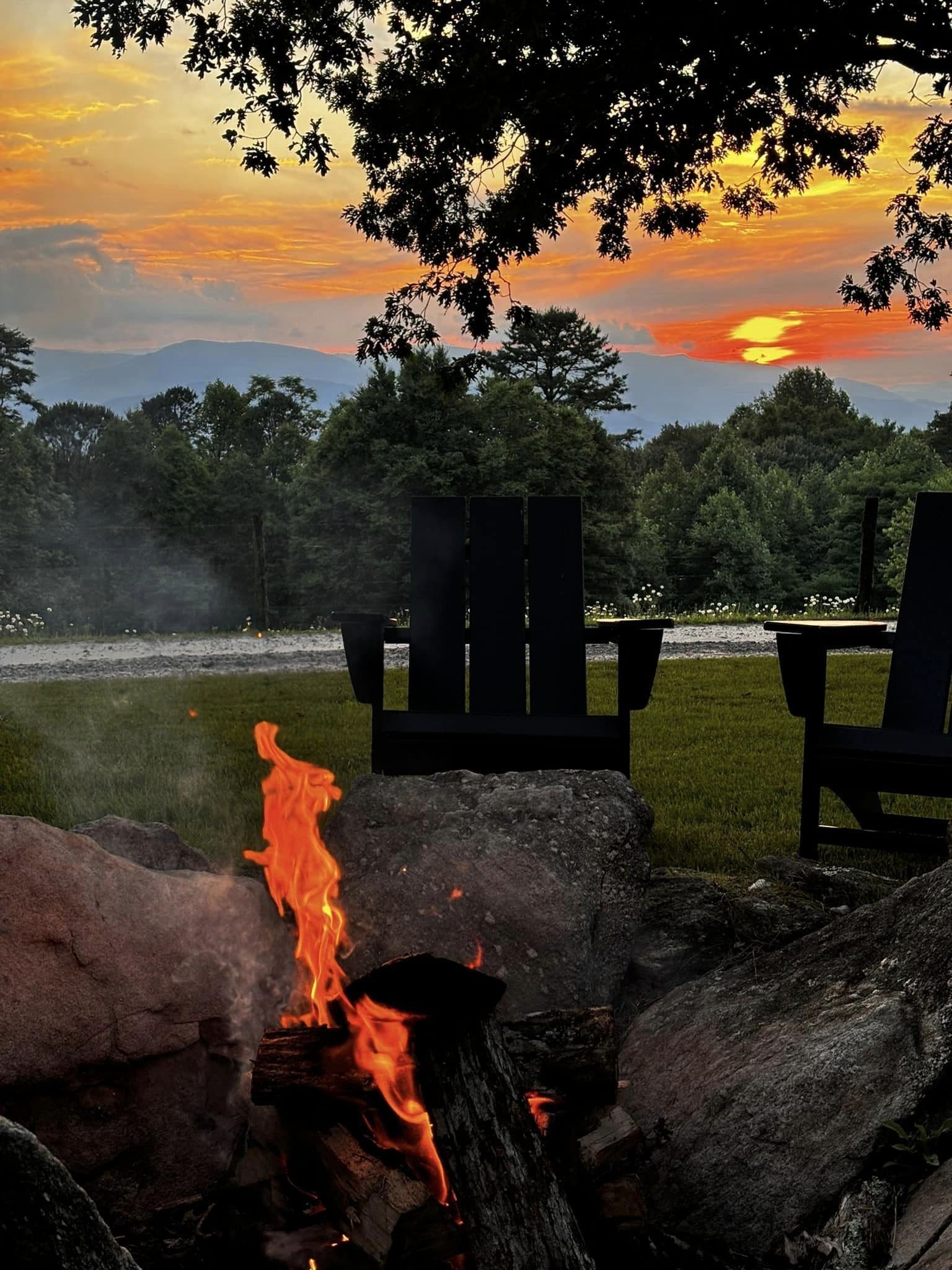 A sunset view with chairs and a fire.