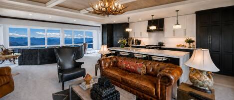 A modern living room with a leather sofa, a dining area, and a kitchen.