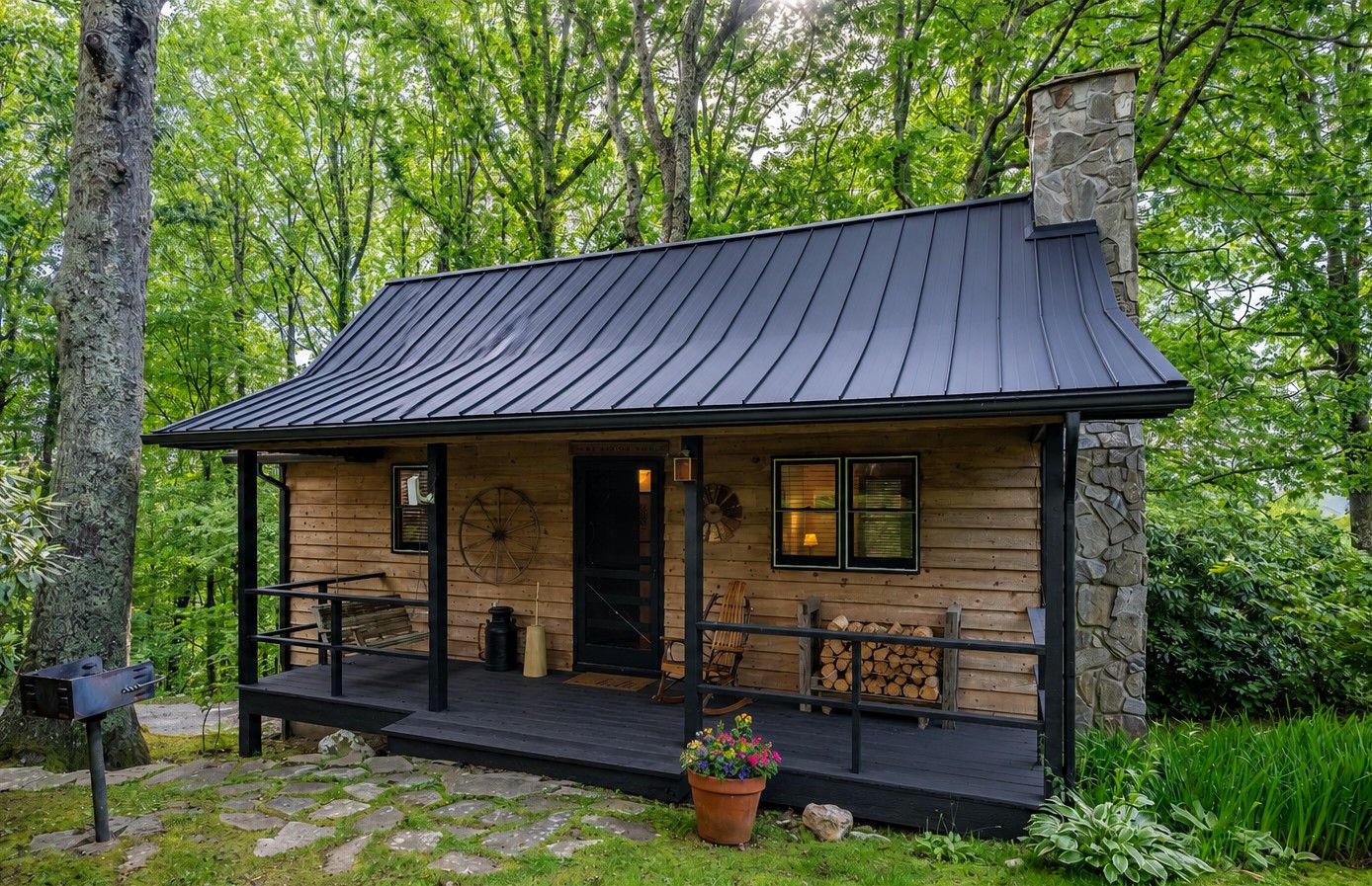 A cabin with a porch, a chimney, and a stone wall.