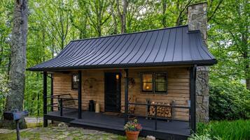 A cabin with a porch, a chimney, and a stone wall.