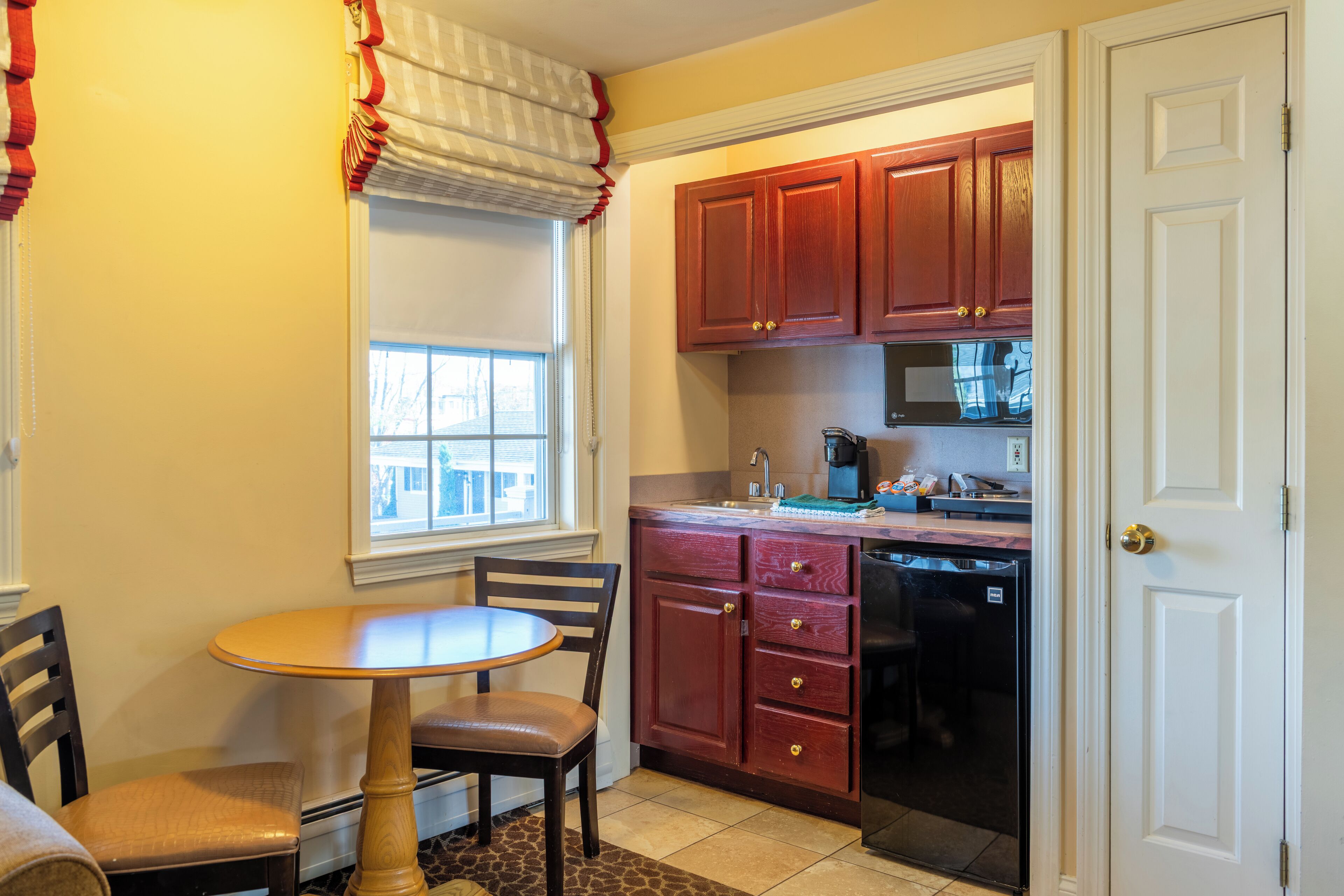 A compact kitchen with wooden cabinets, a built-in microwave, and a dishwasher.