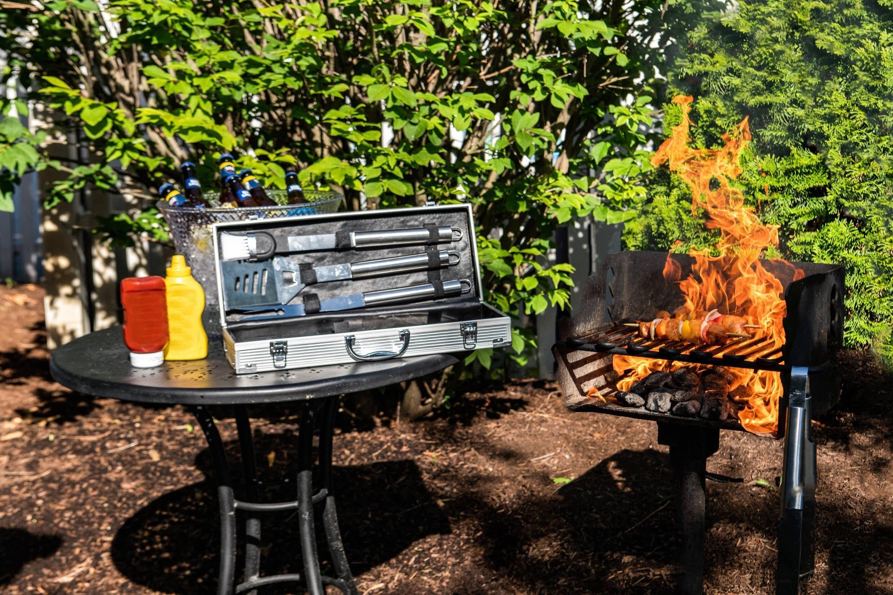 A barbecue setup with a grill, a portable stove, and condiments on a table.