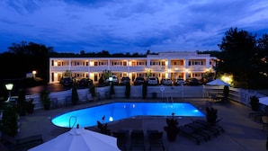 A hotel with a swimming pool, outdoor seating, and a white fence surrounding the area. - Port Inn and Suites Portsmouth, an Ascend Collection Hotel (Portsmouth)
