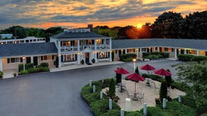 A hotel with a courtyard featuring outdoor seating and red umbrellas. - Port Inn and Suites Portsmouth, an Ascend Collection Hotel (Portsmouth)