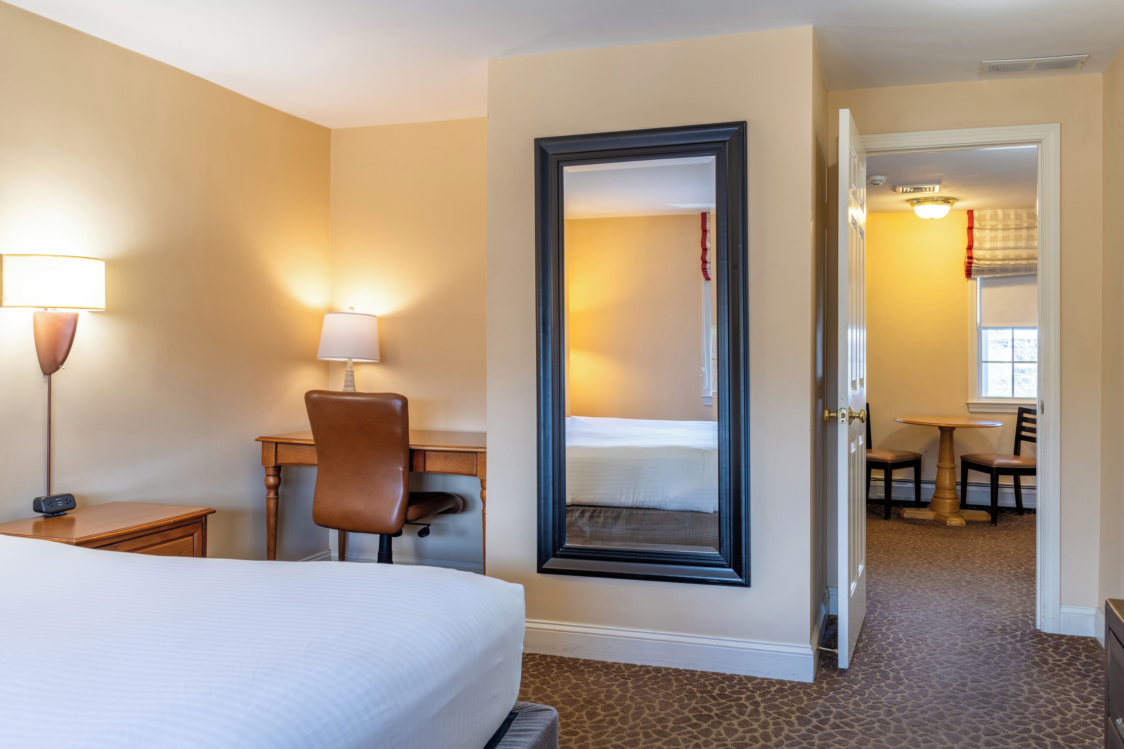 Ein Hotelzimmer mit Bett, Schreibtisch, Stuhl und Spiegel.