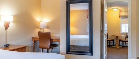 Ein Hotelzimmer mit Bett, Schreibtisch, Stuhl und Spiegel.