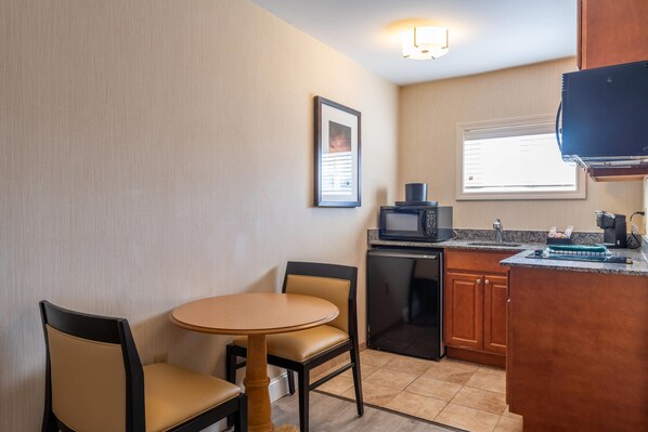 A compact kitchen with a dining area, a microwave, a coffee maker, and a small refrigerator.
