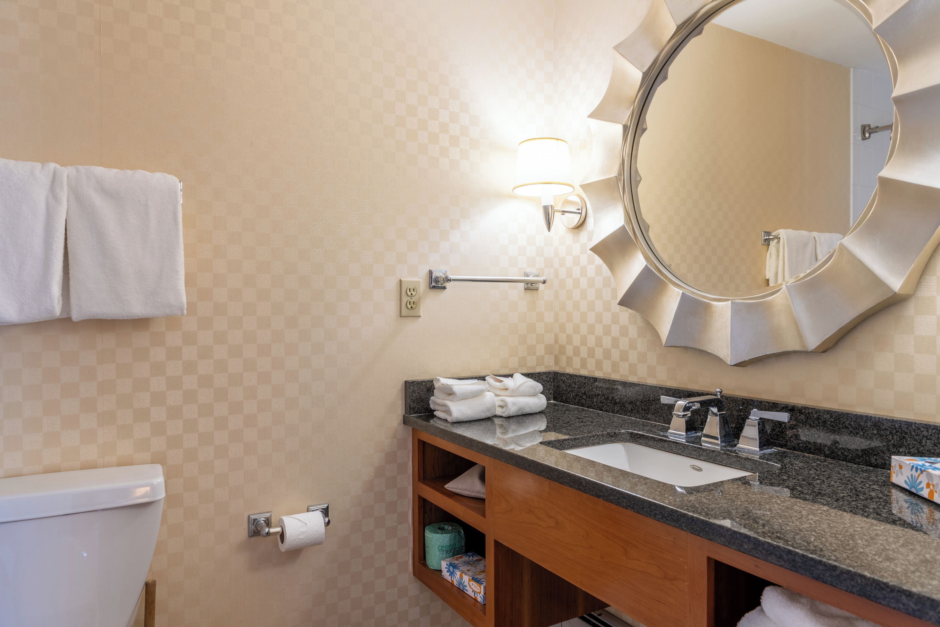 A bathroom with a granite countertop sink, a large mirror, and a towel rack.
