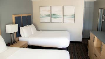 Habitación de hotel con cama doble, mesita de noche con lámpara, cómoda y tres cuadros en la pared.