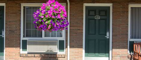 Een gebouw met een groene deur en raam, een bloemenmand en een gevel van baksteen.
