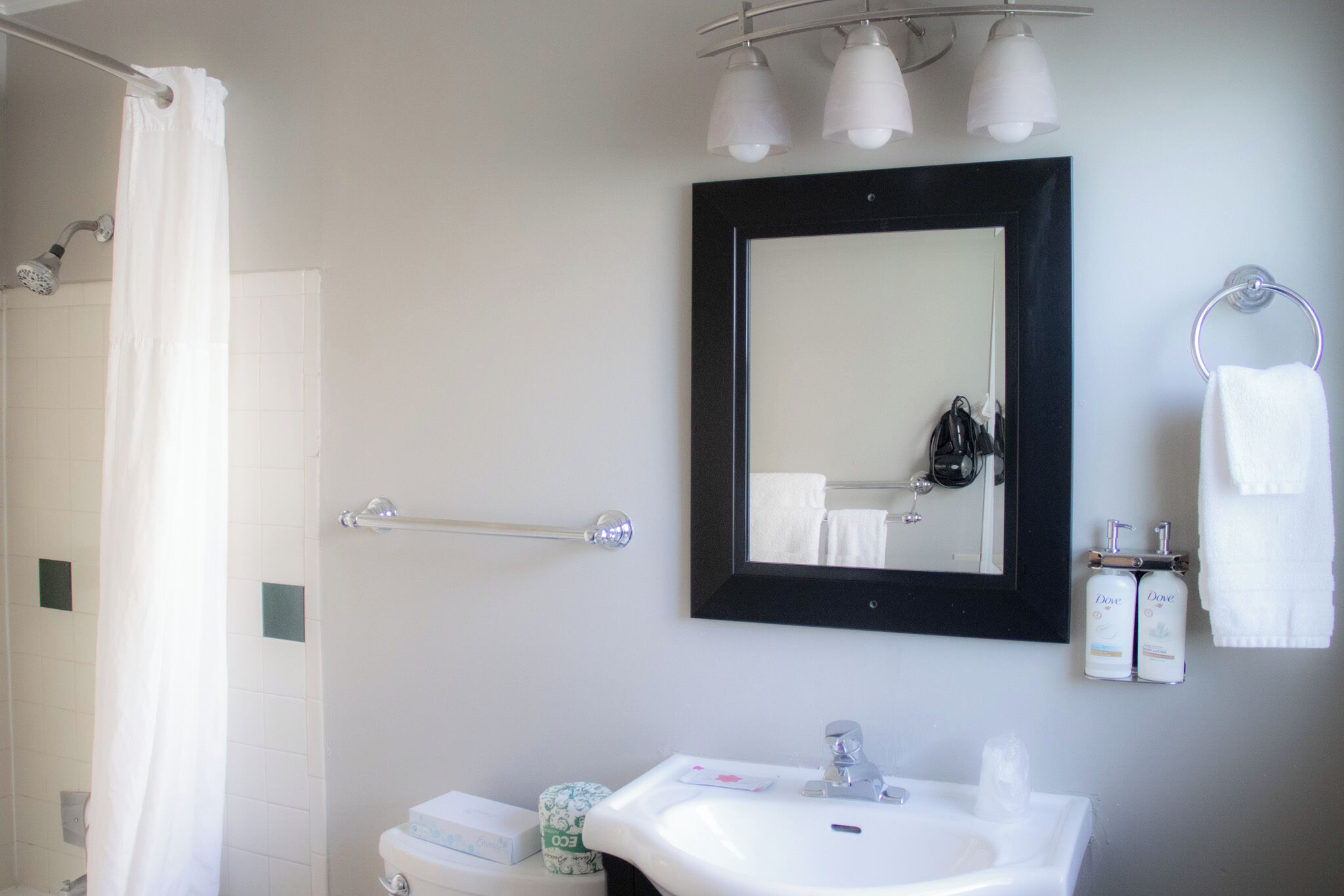 A bathroom with a shower, a sink, a mirror, and a towel rack.