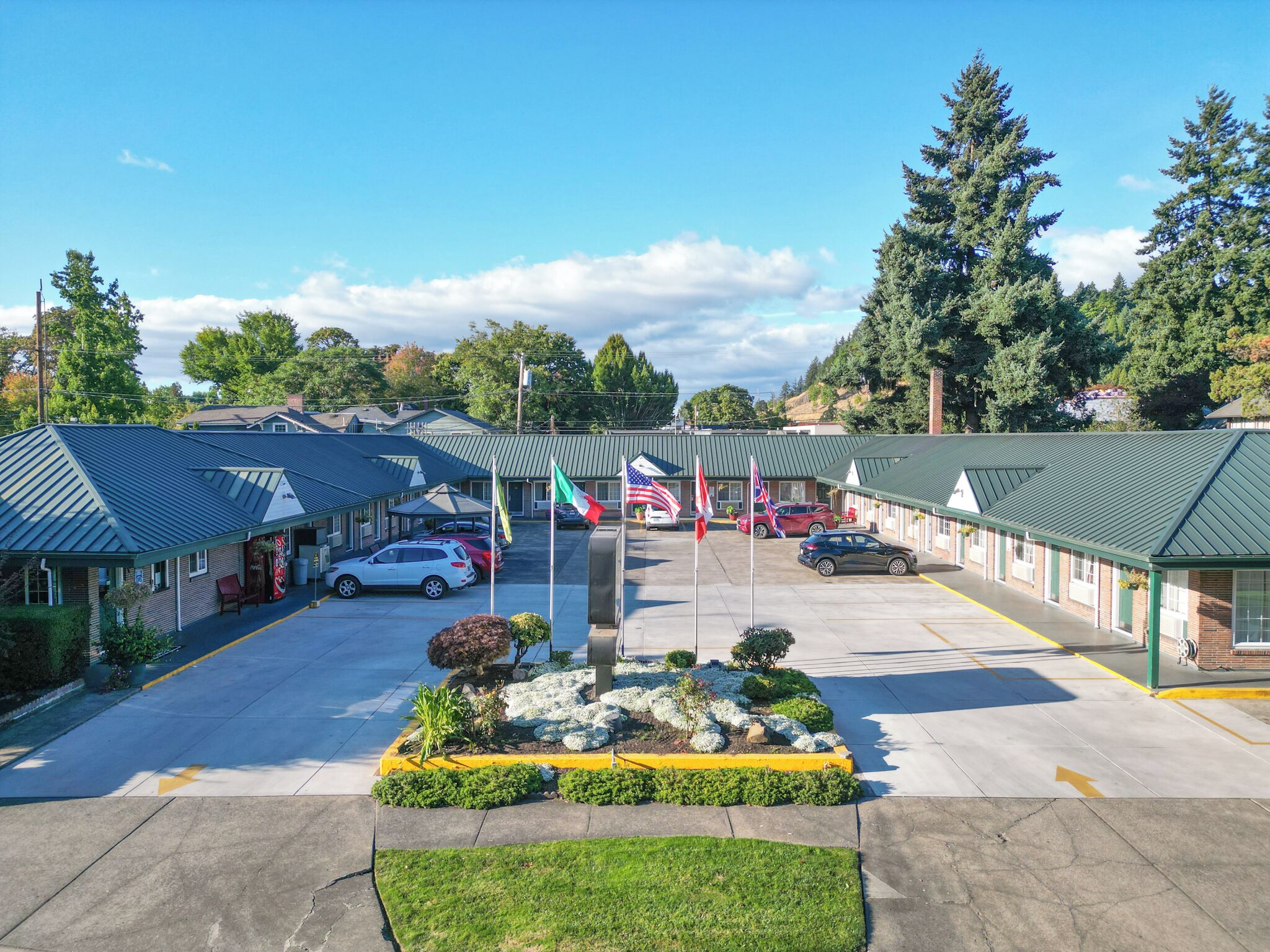 A motel with multiple rooms, a parking lot, and a landscaped garden area.