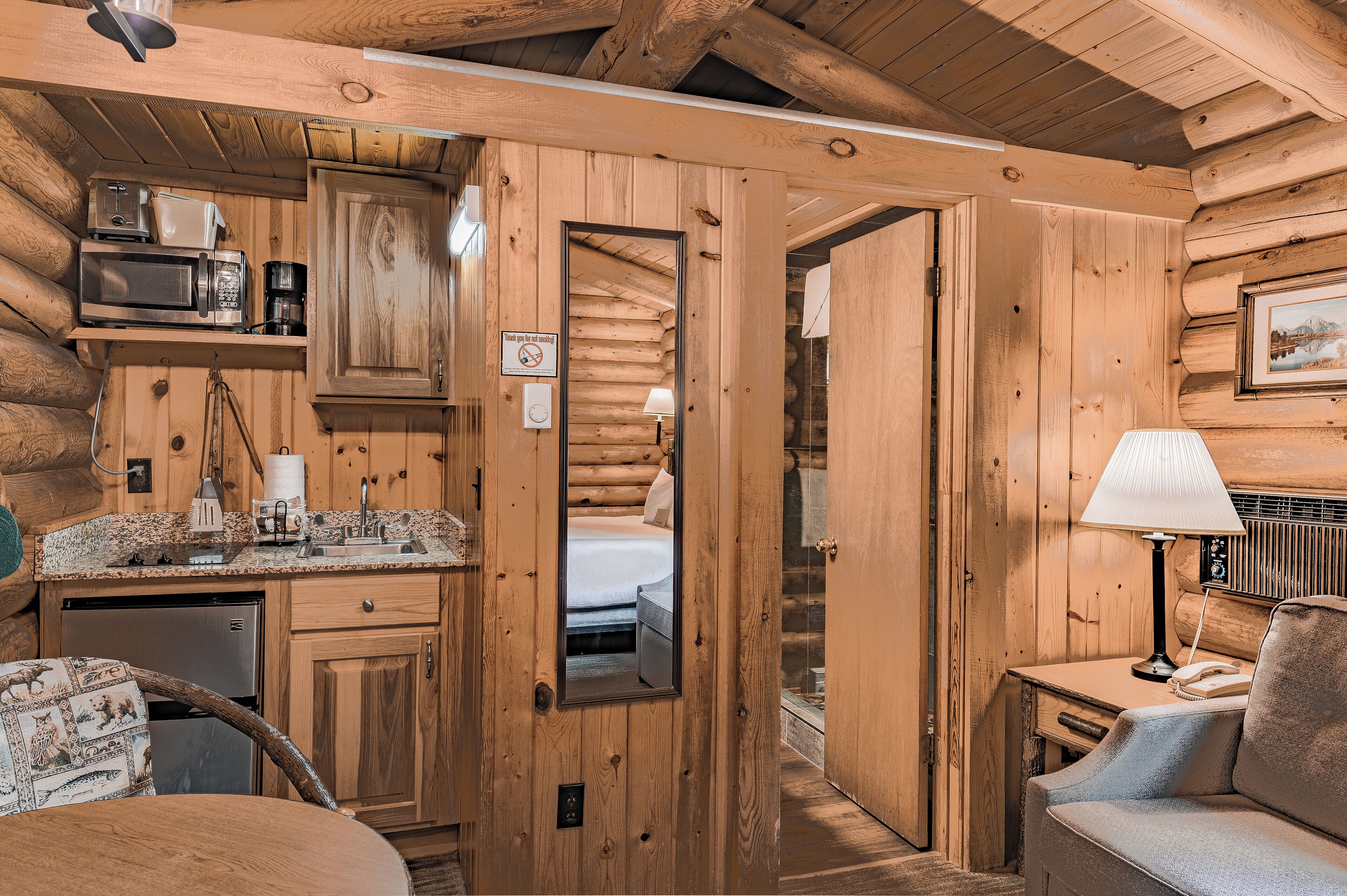 A log cabin interior with a kitchen, a dining area, and a bedroom.