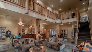 A spacious living area with leather sofas, a coffee table, and a staircase leading to an upper level. - Cowboy Village Resort (Jackson)