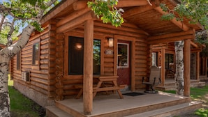 A log cabin with a porch, a number '205' sign, and a table with chairs. - Cowboy Village Resort (Jackson)