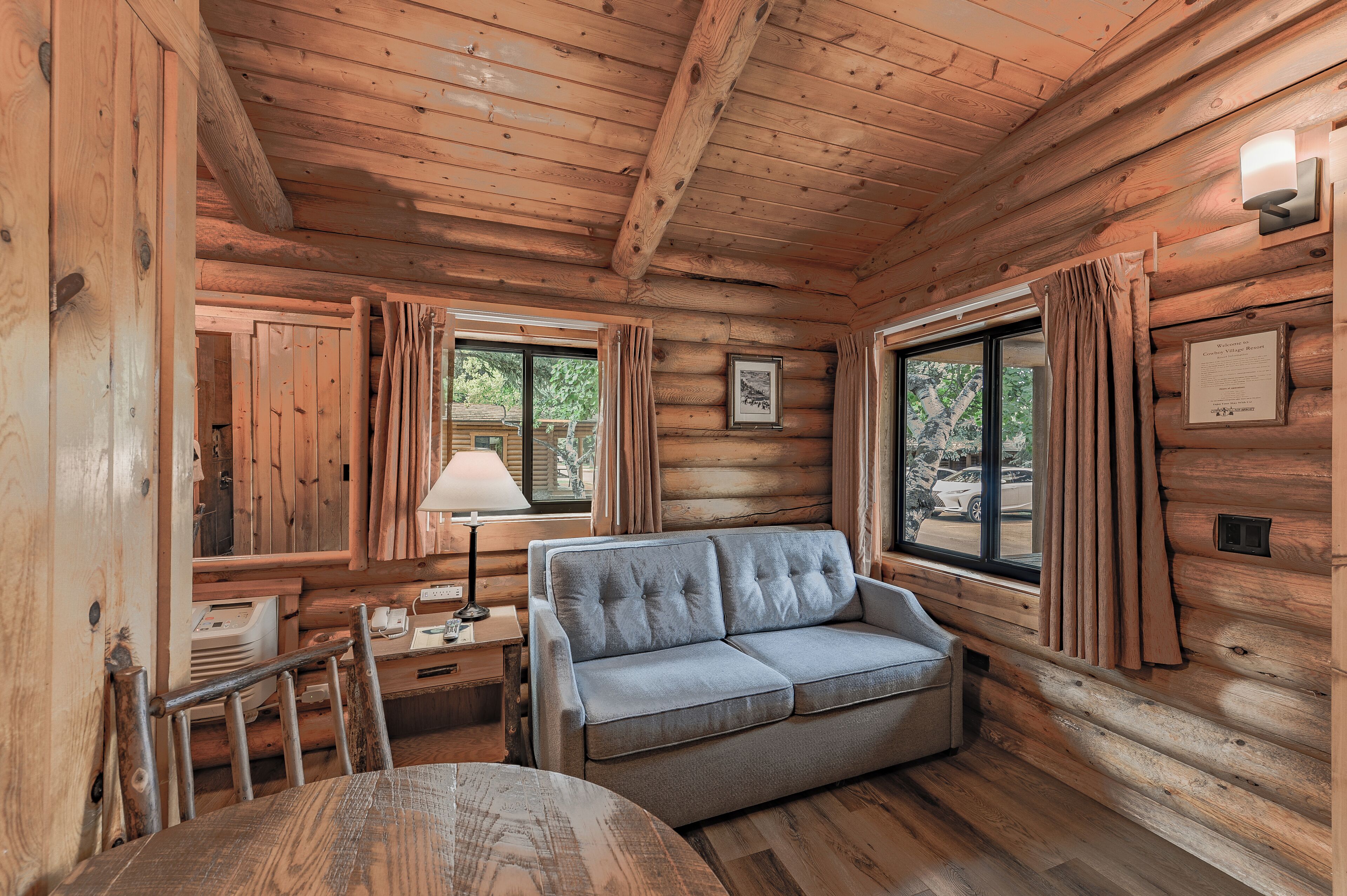 L'intérieur d'une cabane en rondins, avec un canapé, une table et une lampe.