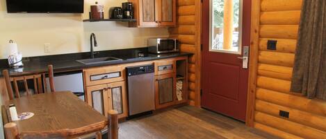 A compact kitchen with wooden cabinets, a microwave, a dishwasher, and a red door.