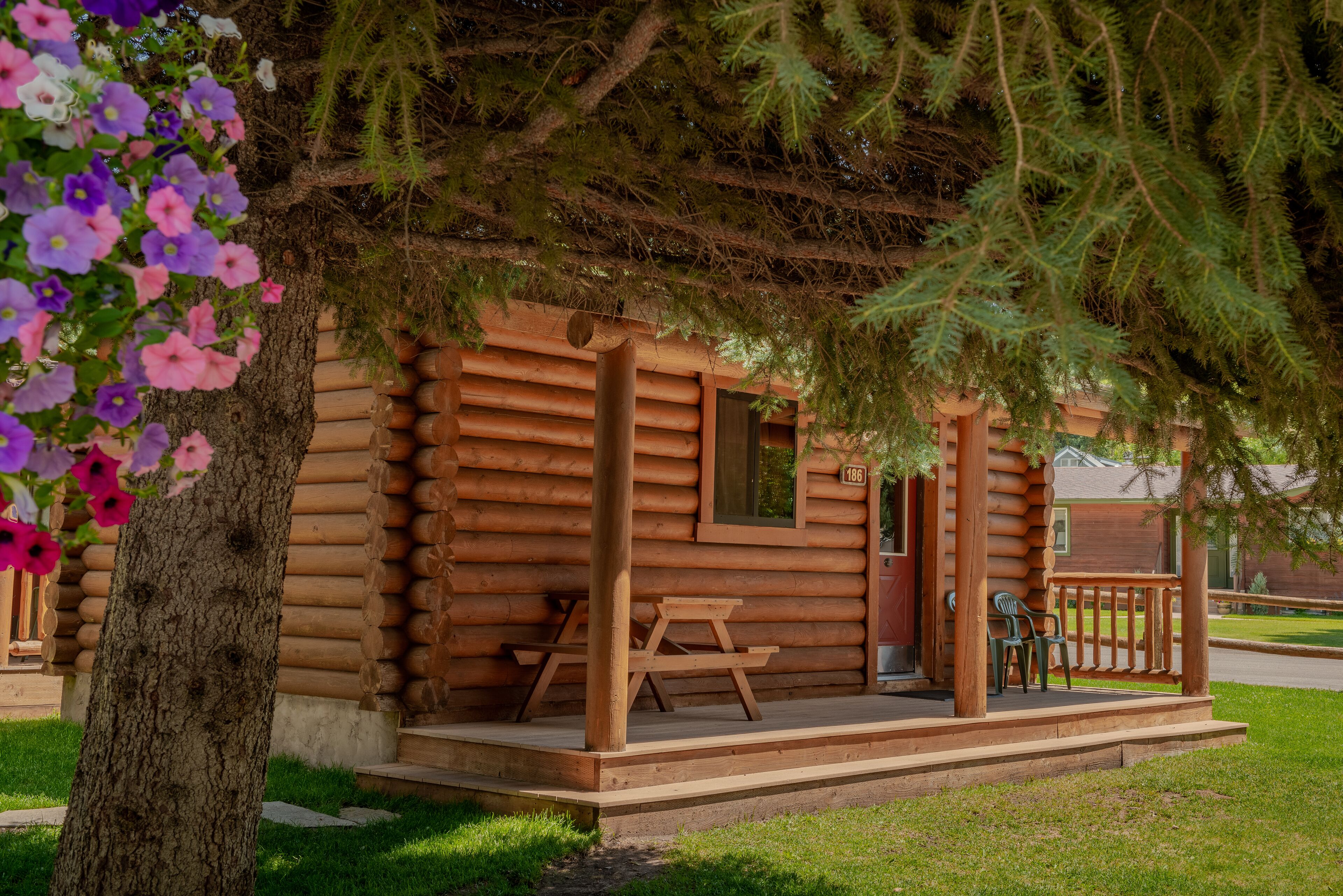 Eine Blockhütte mit Veranda, Picknicktisch und Stühlen.